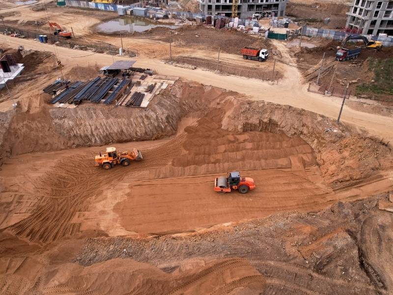Heavy equipment performing site grading and soil preparation for foundation construction on a large development project