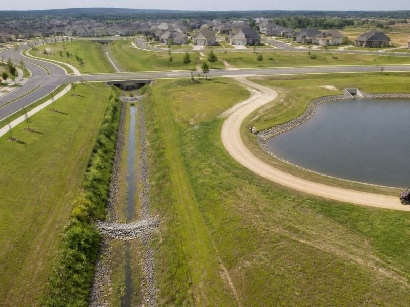 Aerial view of subdivision roads, a drainage channel, and an accessible detention pond in Colorado Springs.
